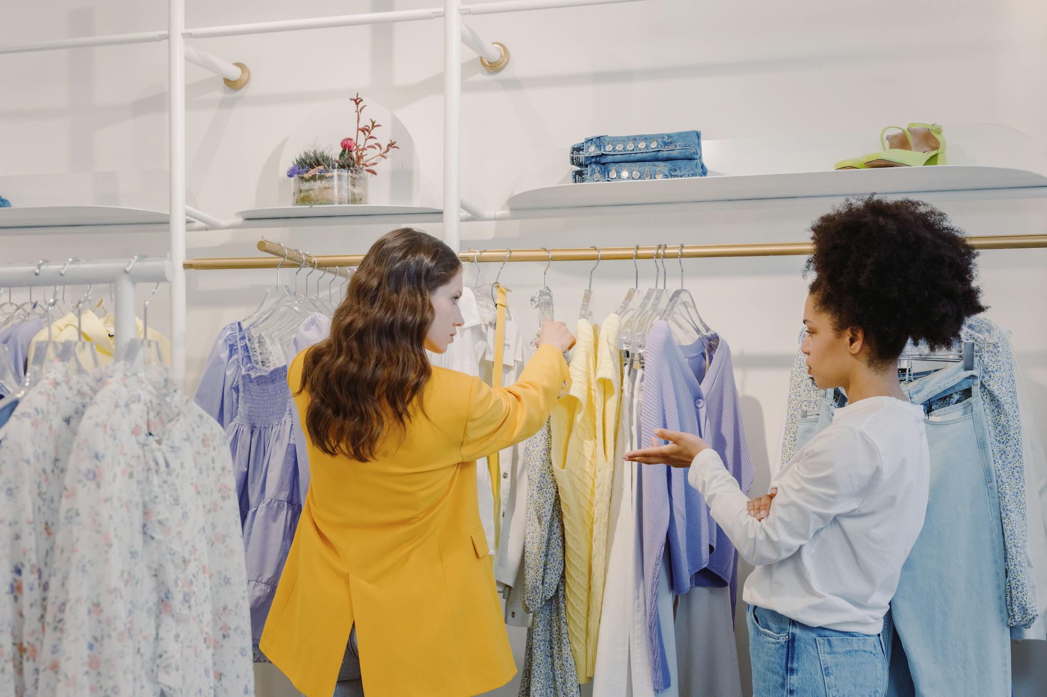 Two women browsing clothing in a stylish boutique, exploring various fashion options.